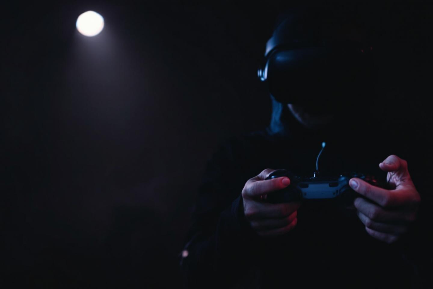 Mains tenant une manette dans l'obscurité, éclairées par la lune