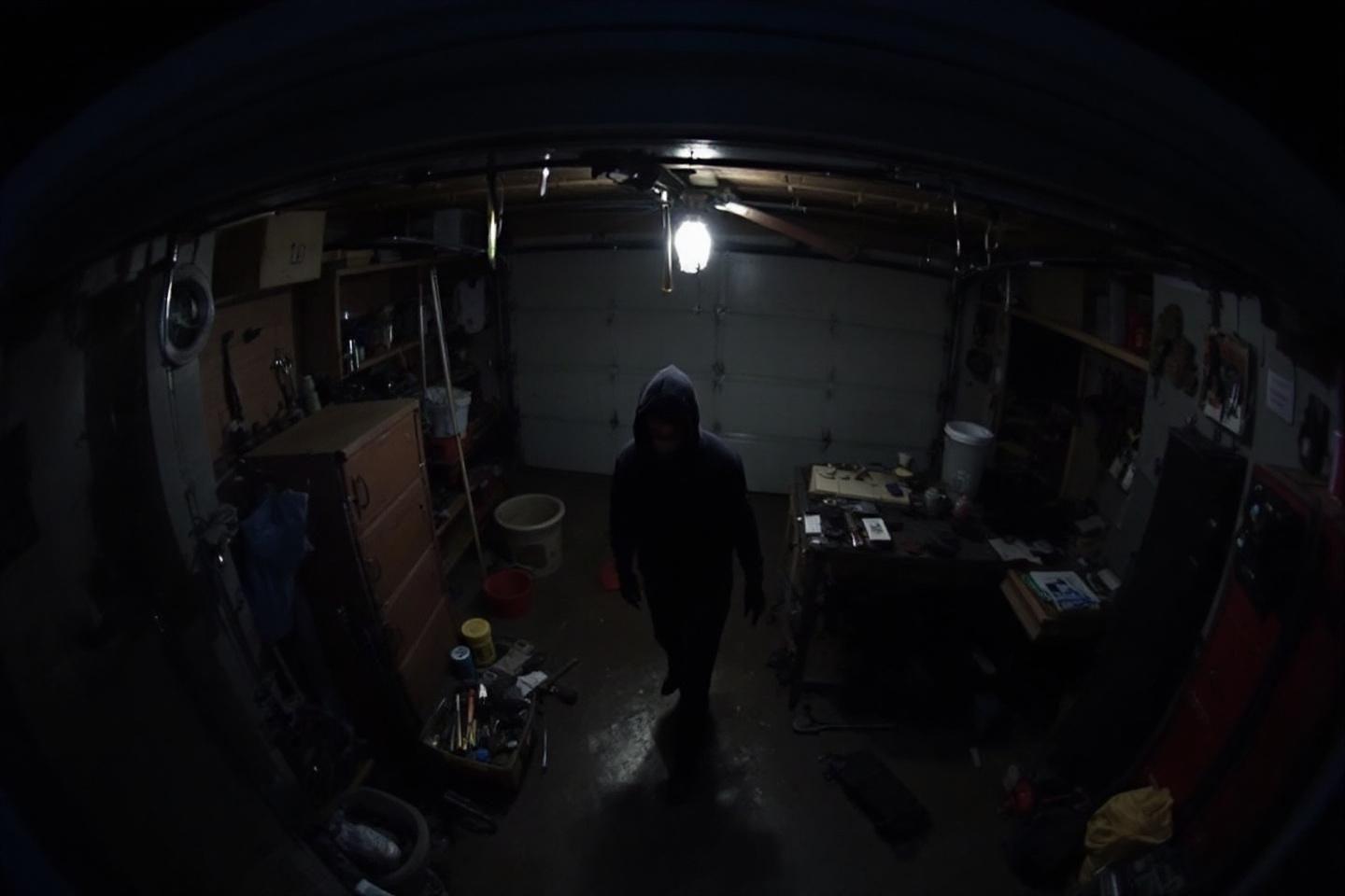 Personne encapuchonnée dans un garage sombre et désordonné