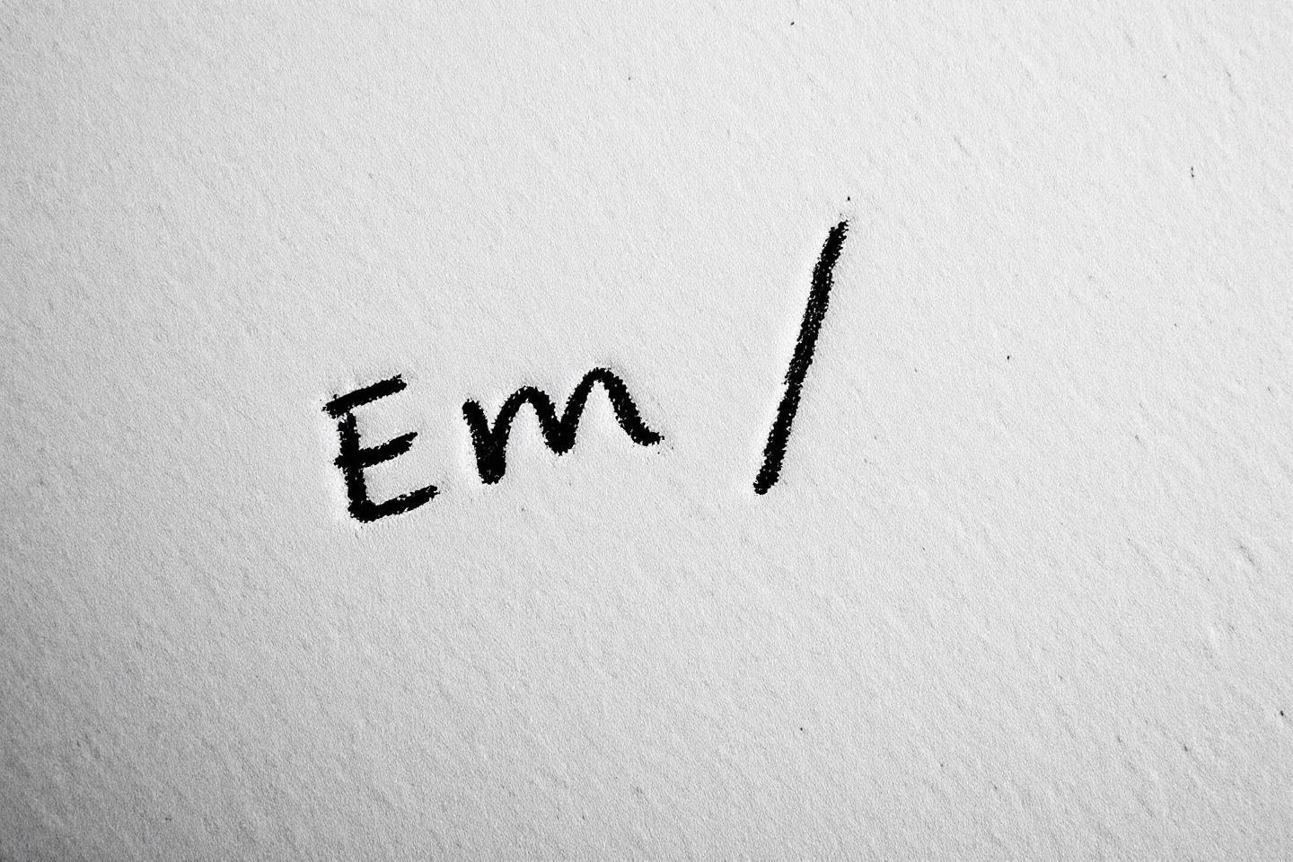 Lettres Em et trait vertical manuscrits sur fond gris clair